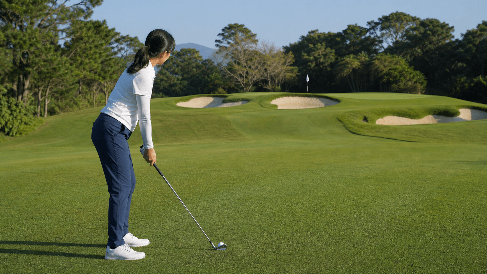 A golfer planning an approach shot toward a guarded green